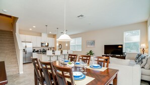 A modern kitchen with white cabinets, a built-in oven, and a stainless steel refrigerator.