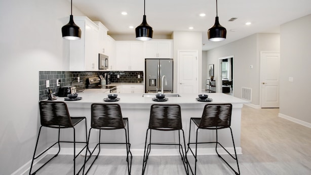 A modern kitchen with a central island, black bar stools, and pendant lighting. - Target Villa Story lake (Kissimmee)