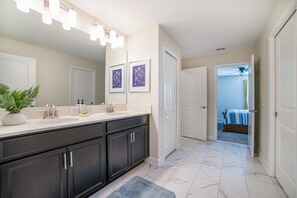 Une salle de bain moderne avec un grand miroir, des meubles sombres et un lavabo blanc.
