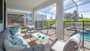 A spacious patio area with a pool, outdoor furniture, and large windows offering views of the surrounding landscape.