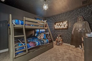 Ein Star-Wars-Schlafzimmer mit Etagenbetten, einem Star-Wars-Poster und einer Darth-Vader-Silhouette.