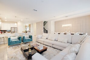 Un salon moderne comprenant un canapé, deux fauteuils, une table basse et un escalier menant à un autre niveau.