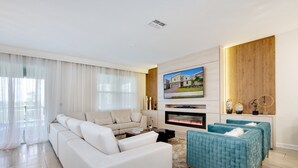 A modern living room with a white sofa, teal ottoman, and a fireplace. - Cruden Villa Champions Gate 8833 (Davenport)