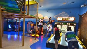 Un salón de juegos recreativos con diversas máquinas y una zona de juegos.