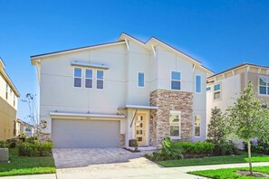 A modern two-story house with a garage, a stone accent wall, and a well-maintained lawn. - Carribean View Villa Solara 2 (Kissimmee)