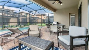 Un patio cubierto con piscina, sillas de descanso y una mesa con sillas.