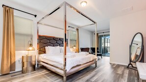 A four-poster bed with a headboard, bedside lamps, and a bedside table. - Carribean View Villa Solara 4 (Kissimmee)