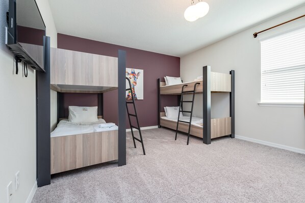 A bedroom with bunk beds, a ladder, a painting, and a window with blinds.