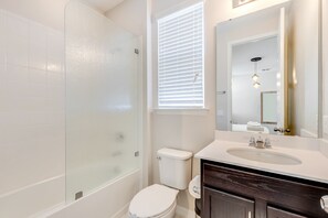 A modern bathroom with a glass shower enclosure, a white toilet, and a vanity with a sink and mirror. - Carribean View Villa Solara 4 (Kissimmee)