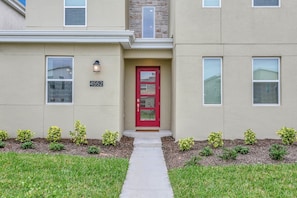 A two-story building with a red door, numbered 4552, and a small porch area with a pathway leading to the entrance. - Target Villa Story lake 54 (Kissimmee)