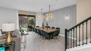 A dining area with a large table, chairs, and a chandelier.