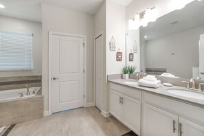 Ein modernes Badezimmer mit einem großen Spiegel, zwei Waschbecken und einer Badewanne.