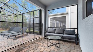 Ein moderner Patio-Bereich mit Glasveranda, einer Couch und einem Glastisch.