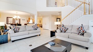A spacious living area with two sofas, a coffee table, and a staircase. - Victoria Villa Porvidence 8 (Davenport)
