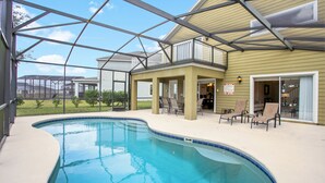 A swimming pool with a covered patio area, outdoor seating, and a view of a residential neighborhood. - Victoria Villa Porvidence 8 (Davenport)
