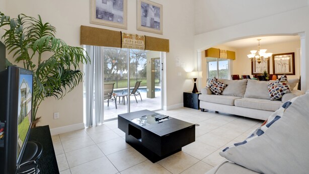 A spacious living room with a large window, a sofa, a coffee table, and a television. - Victoria Villa Porvidence 8 (Davenport)