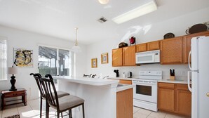 A modern kitchen with wooden cabinets, a white countertop, and a built-in oven. - Pine Villa Winwood Bay (Davenport)