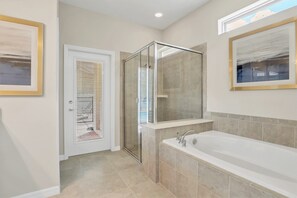 Ein modernes Badezimmer mit einer Glaskabine zur Dusche, einer großzügigen Badewanne und gerahmten Kunstwerken an den Wänden.