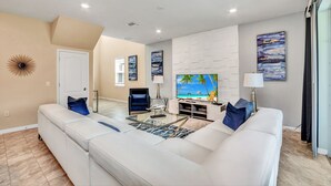 A modern living room with a large flat-screen TV, white sofas, and a glass coffee table. - Oakmoss drive Solterra 3 (Davenport)