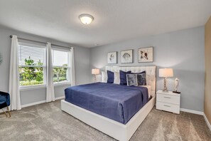 A bedroom with a large bed, two bedside tables, and a window with white curtains. - Oakmoss drive Solterra 3 (Davenport)