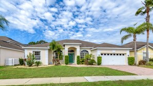 A two-story house with a green front door, a garage, and a well-maintained lawn. - Belfry Drive Villa Highlands Reserve 4 (Davenport)