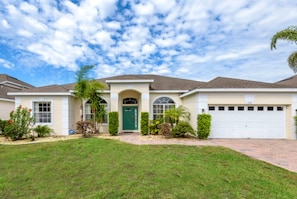 A single-story house with a green front door, a garage, and a well-maintained lawn.