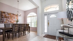 A dining area with a wooden table and chairs, a chandelier, and a large abstract painting on the wall. - Belfry Drive Villa Highlands Reserve 4 (Davenport)