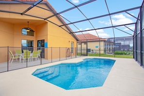 Piscina interna com vista clara para o exterior, área de estar com cadeiras e uma seção coberta com teto.