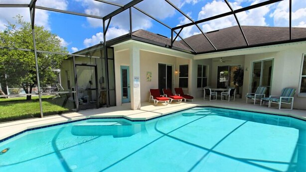 Une piscine avec des chaises longues rouges et un espace patio couvert.