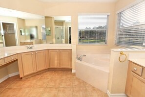 Ein modernes Badezimmer mit einem großen Spiegel, einer Badewanne und einem Fenster mit Jalousien.