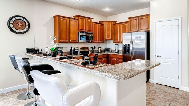 Una cocina moderna con armarios de madera, encimera de granito y electrodomésticos de acero inoxidable.