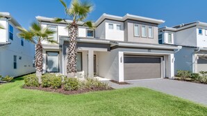 A modern two-story house with a garage, a well-maintained lawn, and palm trees. - Callistoga Villa Sonoma 3 (Kissimmee)