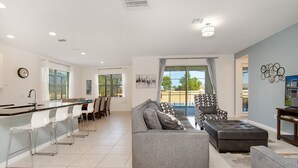 A modern living room with a grey sofa, a patterned armchair, and a dining area with white chairs. - Callistoga Villa Sonoma 3 (Kissimmee)