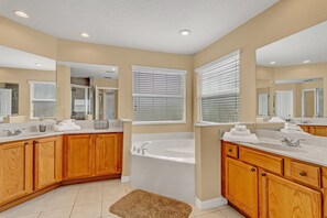 A modern bathroom with wooden cabinetry, a large vanity, a bathtub, and a walk-in shower.