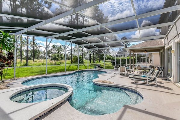 A covered outdoor swimming pool with lounge chairs and a patio area.
