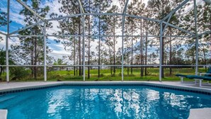 A swimming pool with a clear view of the surrounding trees and a covered area. - Oxford Drive Villa Highlands Reserve (Davenport)