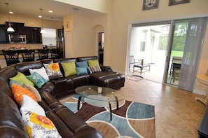 A spacious living room with a leather sectional sofa, a glass coffee table, and a patterned rug.