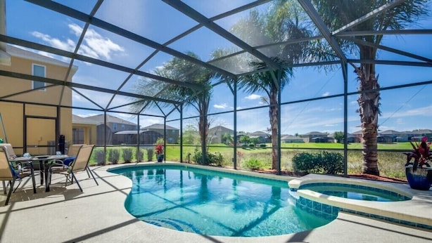 A pool area with a glass enclosure, lounge chairs, and a view of a golf course. - Adulusiia Loop Villa Mabella (Davenport)