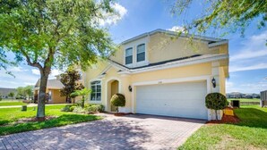 A two-story house with a garage, a brick driveway, and well-maintained landscaping. - Adulusiia Loop Villa Mabella (Davenport)