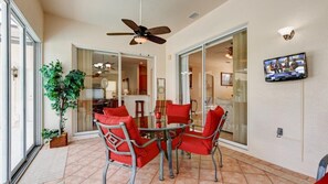 A dining area with a round table and red chairs, a ceiling fan, and a television on the wall. - 354pd Golf View Villa With Spa (Davenport)