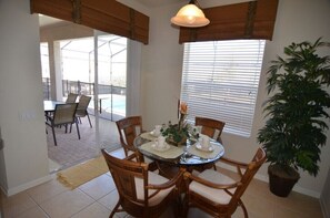 Un coin repas avec une table ronde, quatre chaises et une plante en pot.
