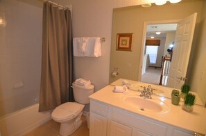 Une salle de bain équipée de toilettes, d’un lavabo et d’un rideau de douche.