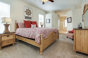 Une chambre à coucher avec un lit en bois, une table de chevet, une commode et un ventilateur de plafond.