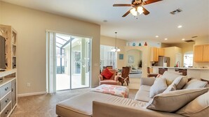 A spacious living room with a large sofa, a dining area with chairs, a kitchen with cabinets, and a ceiling fan. - 4 Bed Villa 732bd (Davenport)