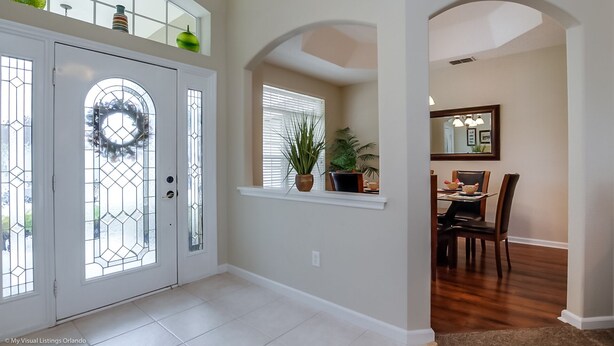 A spacious entryway with a glass door, a dining area with a table and chairs, and a large mirror on the wall. - 4 Bed Villa 732bd (Davenport)