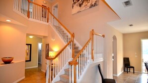 A spacious interior with a wooden staircase, a dining area, and a view of the outdoors. - Bonville Drive Villa Highlands Reserve (Davenport)