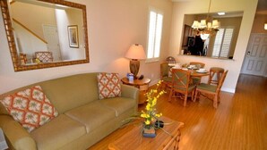 A living room with a sofa, coffee table, and dining area with chairs. - 3500cal Stunning Town Home In Regal Plams (Davenport)