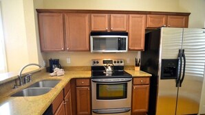 A kitchen with wooden cabinets, a stainless steel oven, a microwave, and a refrigerator. - 3500cal Stunning Town Home In Regal Plams (Davenport)