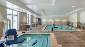 An indoor swimming pool area with two pools, seating, and a lifeguard chair.