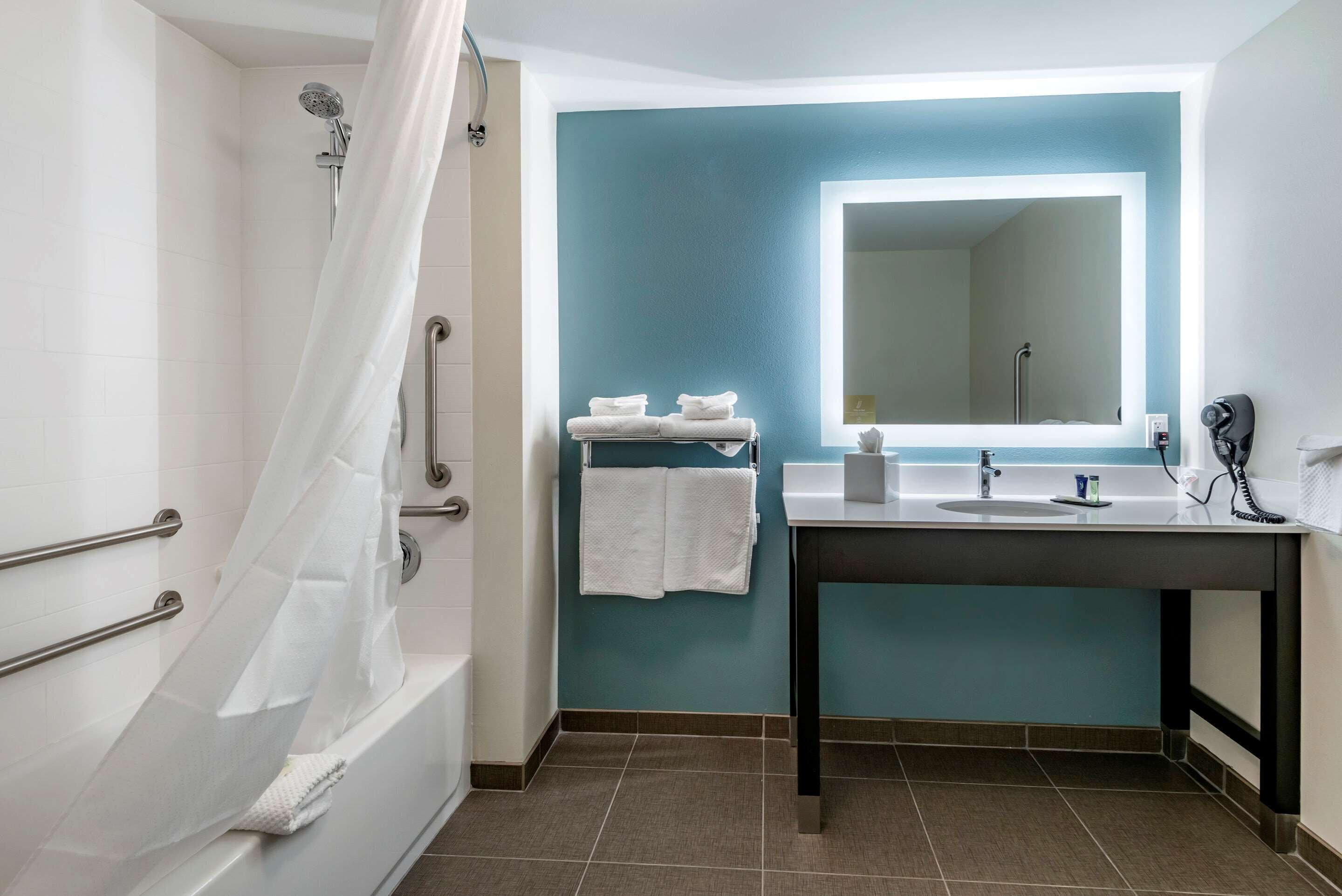 A bathroom with a bathtub, a sink, a mirror, and a shower.